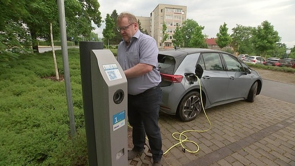 Ein Mann betankt sein E-Auto mit Strom.