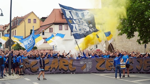Fans des FC Carl Zeiss Jena laufen mit Fahnen und Pyrotechnik durch die Stadt