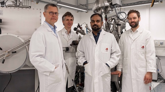 Die Wissenschaftler Prof. Dr. Andrey Turchanin, Dr. Falk Eilenberger, Dr. Antony George und Laborleiter Dr. Christof Neumann stehen in einem Labor zusammen.