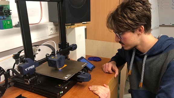 Ein jungermann arbeitet an einem 3D-Drucker.