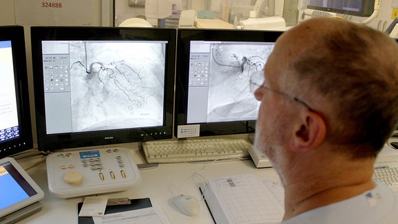 Ein Mann sitzt im Herz-Labor vor einem Monitor.