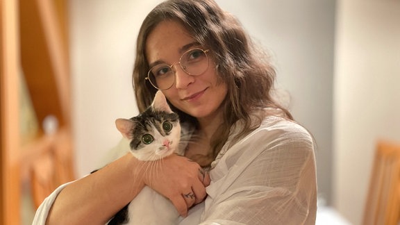 Eine junge Frau (Vanessa Sonntag) hält eine weiß-schwarze Katze im Arm