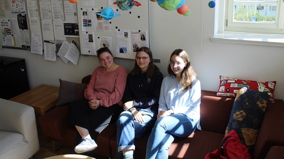 Drei Schülerinnen beim Kickern, beim Sitzen auf einem Sofa, der Schulleiter in der Bibliothek und auf dem Schulhof der Jenaplanschule. 