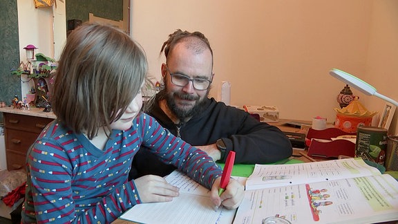 Ein Mädchen erledigt mit ihrem Vater Hausaufgaben.