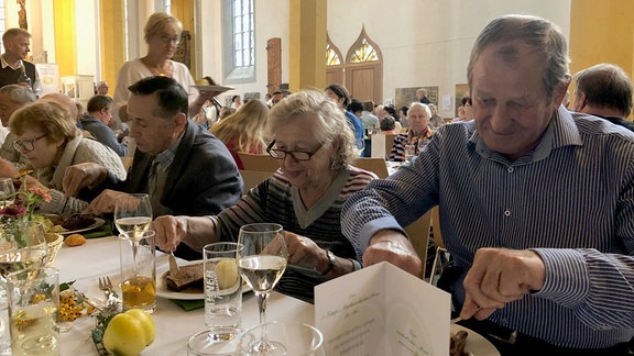 Menschen essen an einer langen Tafel.