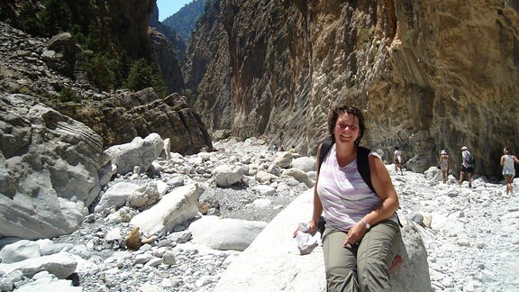 Frau sitzt auf Stein vor Schlucht auf Kreta.