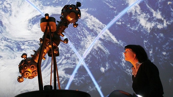 Eine Frau betrachtet einen Projektor im Planetarium.