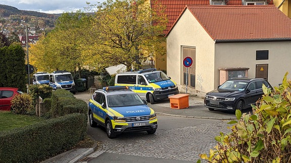 Mehrere Polizeiautos vor einem Wohnhaus.