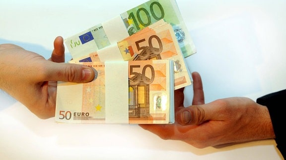 Eine Hand übergibt an eine andere Euroscheine.
