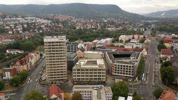 Stadtansicht von Jena von oben. Im Hintergrund sind Berge zu sehen.