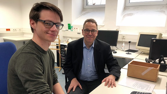 Doktorand Paul Winkler und Wahrnehmungsforscher Prof.Dr. Stefan Schweinberger sitzen an einem PC.