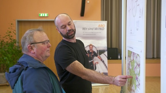 Ein Mann der Abo Wind AG erklärt den Bebauugsplan des Windparks im Saale-Holzland-Kreis.