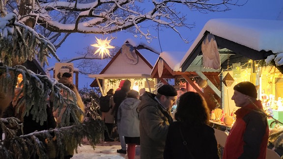 Menschen vor erleuchteten Ständen: Weihnachtsmarkt der Wünsche auf der Leuchenburg