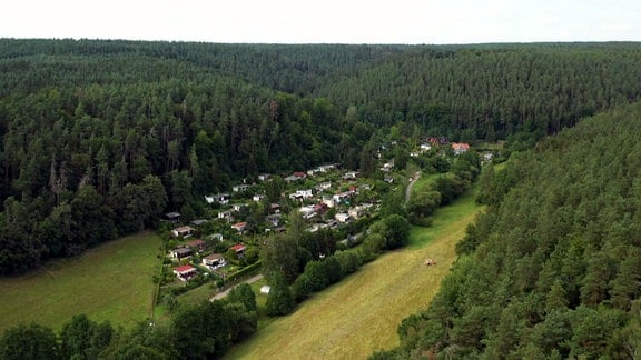 Eine Wochenendhäuser-Siedlung an einem Wald von oben.