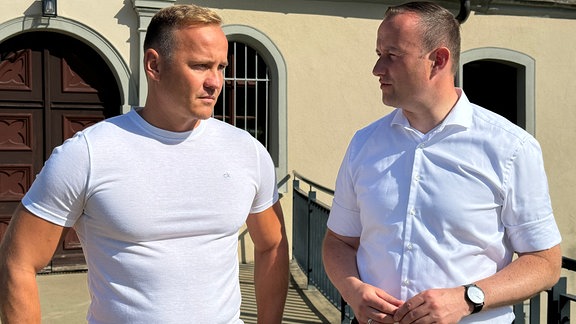 Saale-Orla-Kreis-Landrat Christian Herrgott unterhält sich mit Mann in weißem Shirt