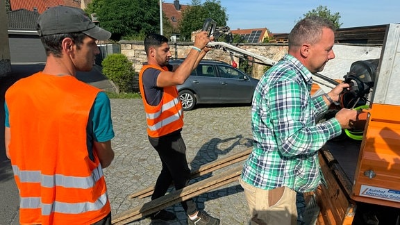 Männer laden Werkzeug aus Kleinlaster von Bauhof