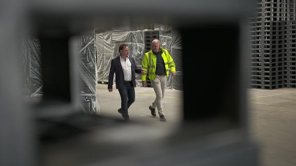 Zwei Männer laufen durch eine Lagerhalle