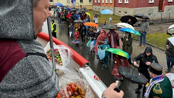 Ein Mann wirft Süßigkeiten von einem Wagen zu den Zuschauern