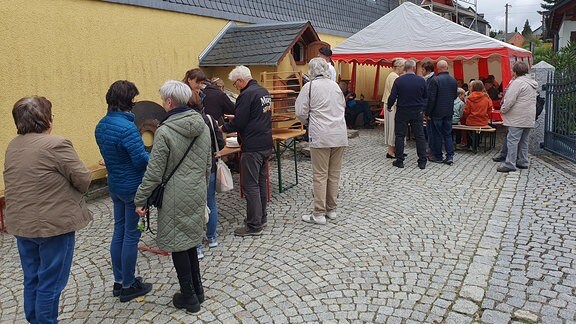 Menschen stehen Schlange an einem Kuchenstand.