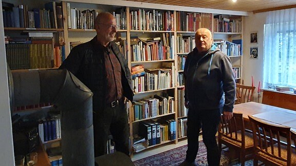 Zwei Männer in einem Raum mit vielen Büchern.