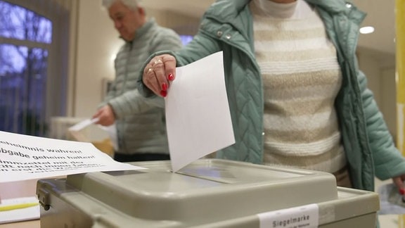 Zur Landratswahl im Saale-Orla-Kreis wirft eine Frau den Stimmzettel in die Wahlurne.