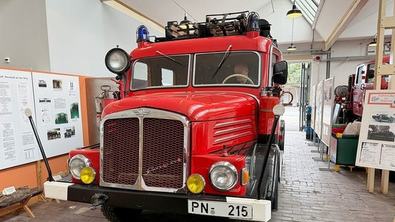 Eine rote Oldtimer-Feuerwehr steht in einer Halle.