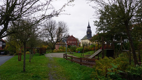 Der Spielplatz in der Dorfmitte von Paska. Im Hintergrund die Kirche.