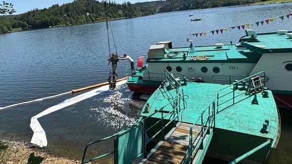 Ein Baukran hebt ein Motorteil von einem Schiff.