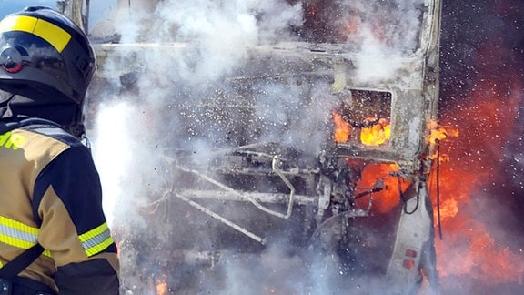 Ein Feuerwehrmann löscht einen brennenden Lkw