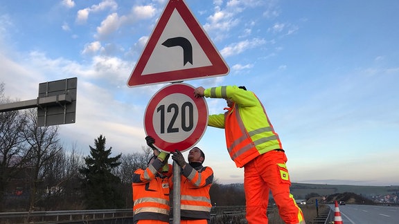 Bauarbeiten bringen an einer Autobahn ein 120-Schild an