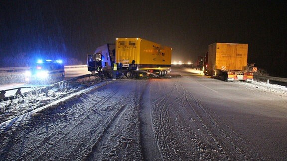 Ein Lkw steht bei Schnee quer auf der Autobahn.