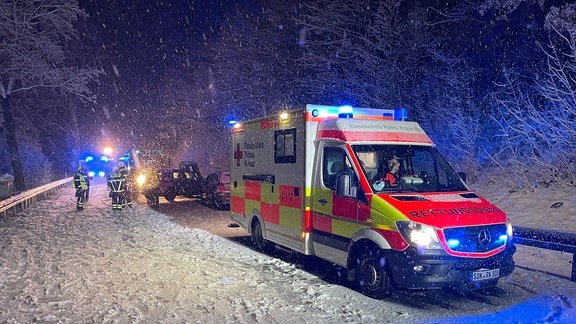 Ein Rettungswagen an einer Unfallstelle im Schnee.