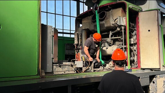 Zwei Männer mit Helm verbauen ein Eisenbahn-Teil.