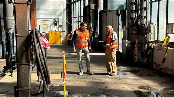 Zwei Männer mit Warnwesten unterhalten sich im Bahnwerk Saalfeld.