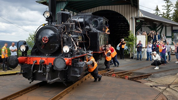 Helfer schieben die Dampflok „Luci“ vor Beginn des Jubiläumsfests 100 Jahre Bergbahn Oberweißbach auf die Flachstrecke. 