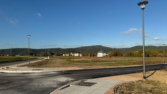  In Saalfeld-Graba soll ein neues Wohngebiet mit bis zu 81 Baugrundstücken entstehen. Straße und Bürgersteig sind fertig, die Laternen stehen.