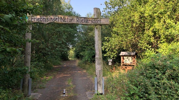 Ein hölzerner Torbogen über einen Pfad trägt die Aufschrift "Erlebnisinsel Natur Rückersdorf"