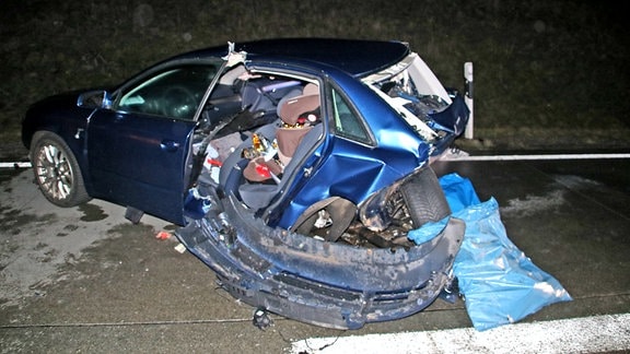 Ein völlig zerstörtes blaues Auto nach einem Unfall auf der Autobahn