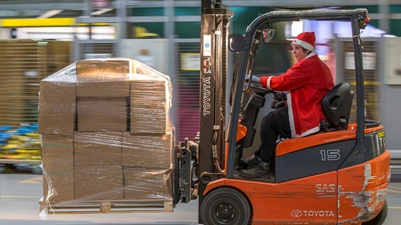 Im Weihnachtsmannkostüm befördert ein Mitarbeiter Pakete im Paketzentrum Nohra (Thüringen).