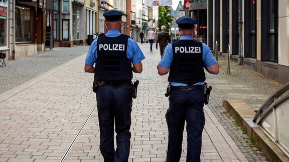 2 Polizisten gehen eine Einkaufsstraße entlang