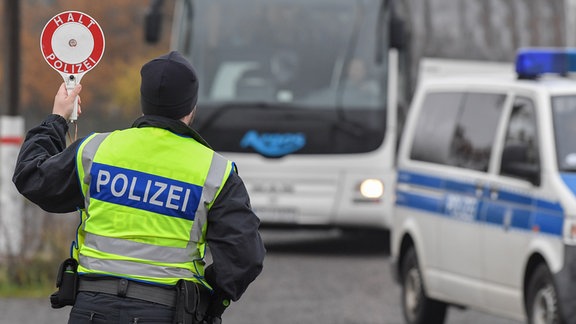 Ein Beamter der Bundespolizei winkt zu einer Kontrolle einen Reisebus auf einen Rastplatz an der Autobahn 12.