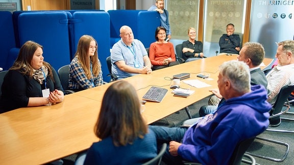 Menschen sitzen für ein Meeting in einem Raum