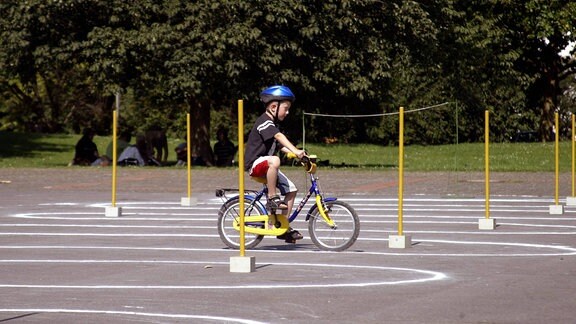 Junge mit Fahrrad und Helm auf einem Geschicklichkeitsparcours