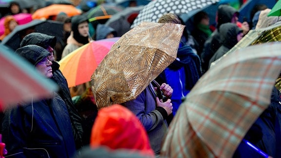Besucher eines Festivals verfolgen ein Konzert im strömenden Regen.