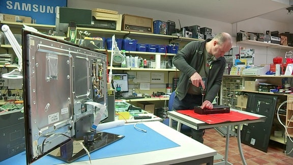 Ein Mann repariert in einer Werkstatt ein Elektrogerät.