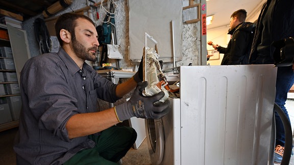 Ein Mann repariert eine defekte Waschmaschine in der Werkstatt der Erfurter Reparatur-Initiative Build, Share and Repair