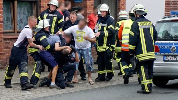 Drei Männer behindern nach einem Unfall die Arbeit der Rettungskräfte.