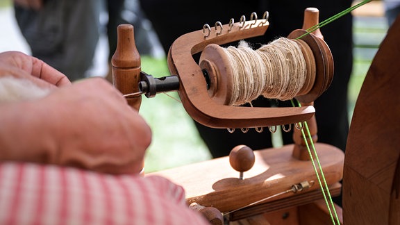 Eine Ausstellerin sitzt an einem Spinnrad.