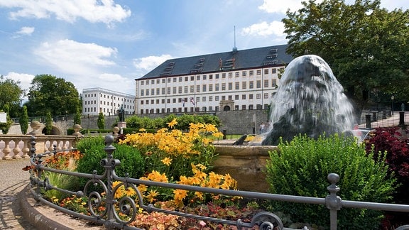 Blick auf Schloss Friedenstein, im Vordergrund blühende Blumen und ein Springbrunnen