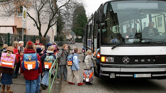 Schüler steigen in einen Schulbus ein.